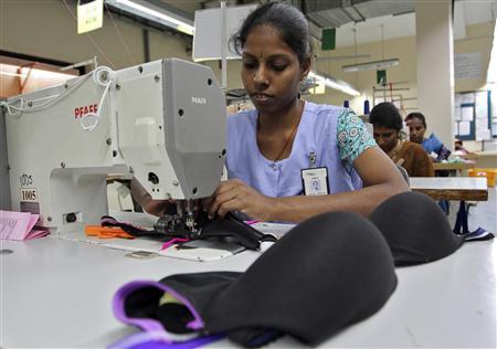 Garment worker stitching lingerie at a sewing machine in a manufacturing unit, demonstrating quality-controlled apparel production